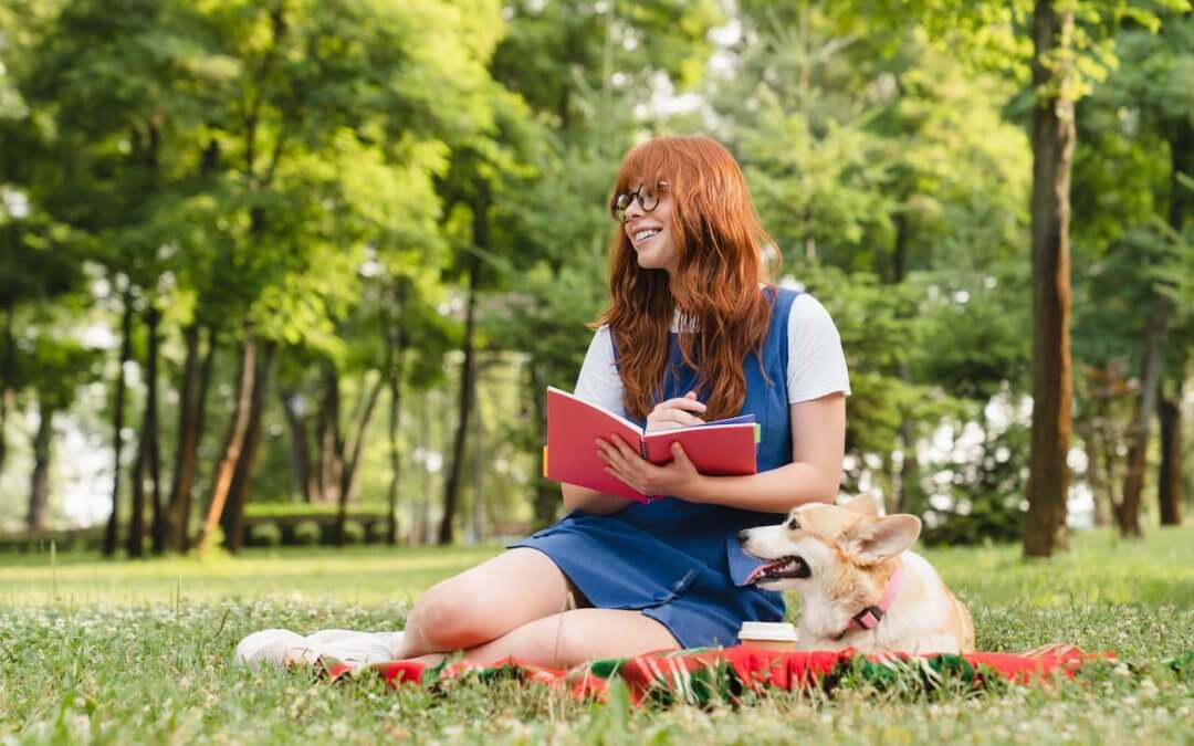 Author reading a poetry book while sitting with her dog.