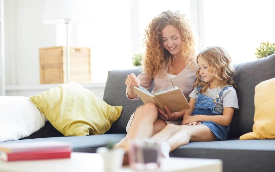 Parent and child reading together on a couch.