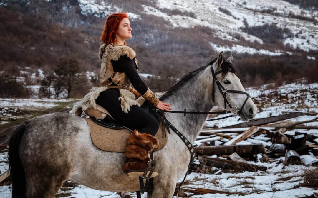 Red-haired woman riding on a horse.